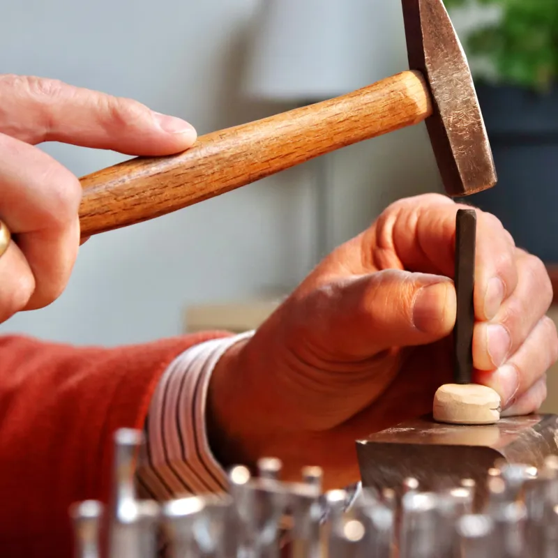 Hände mit einem Hammer über einer Gebetsnuss